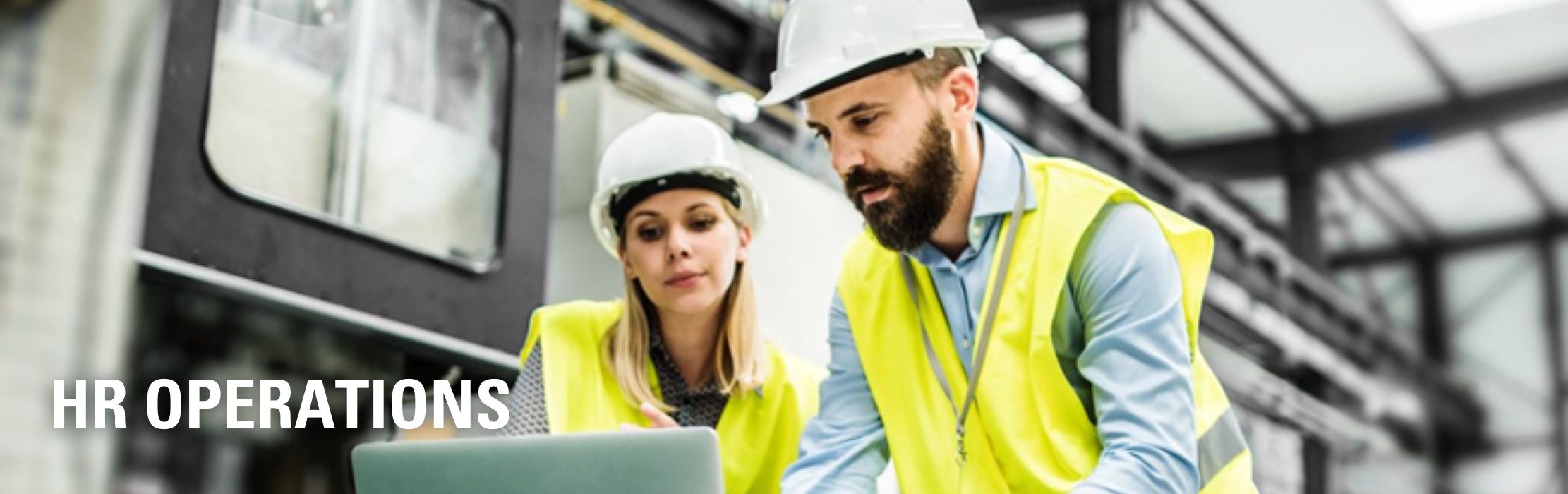 Employees in safety gear looking at a laptop computer.